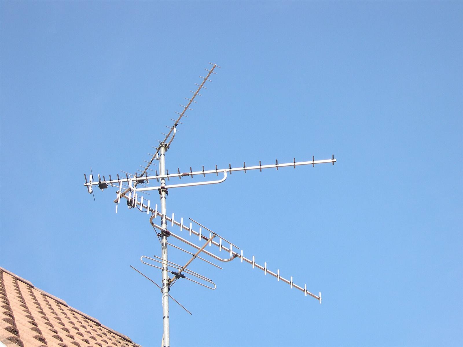 TV aerial on a tiled rooftop against a blue sky